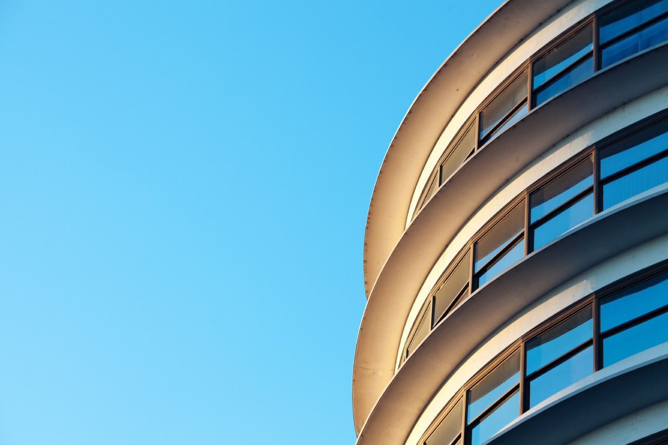 Balcón con terraza de madera, plantas y el horizonte de la ciudad de fondo, bañado por la luz del sol.