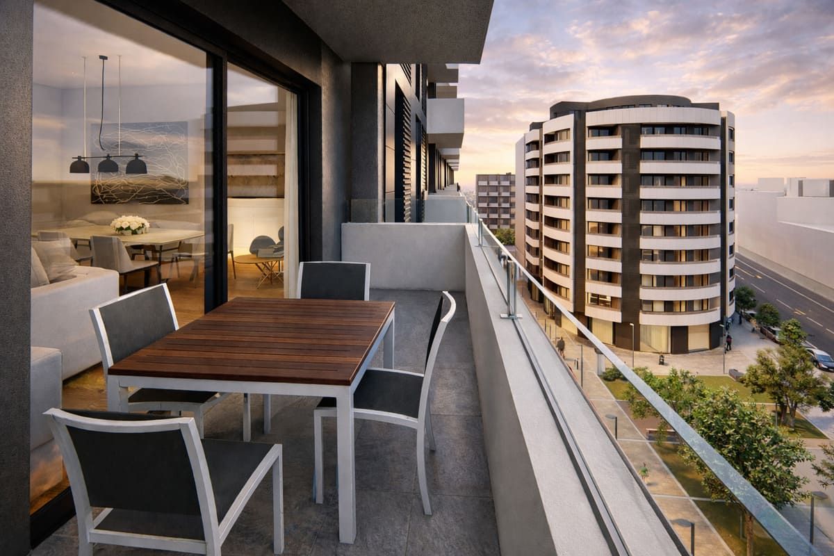 Balcón con mesa y sillas con vista a los edificios de la ciudad al atardecer.