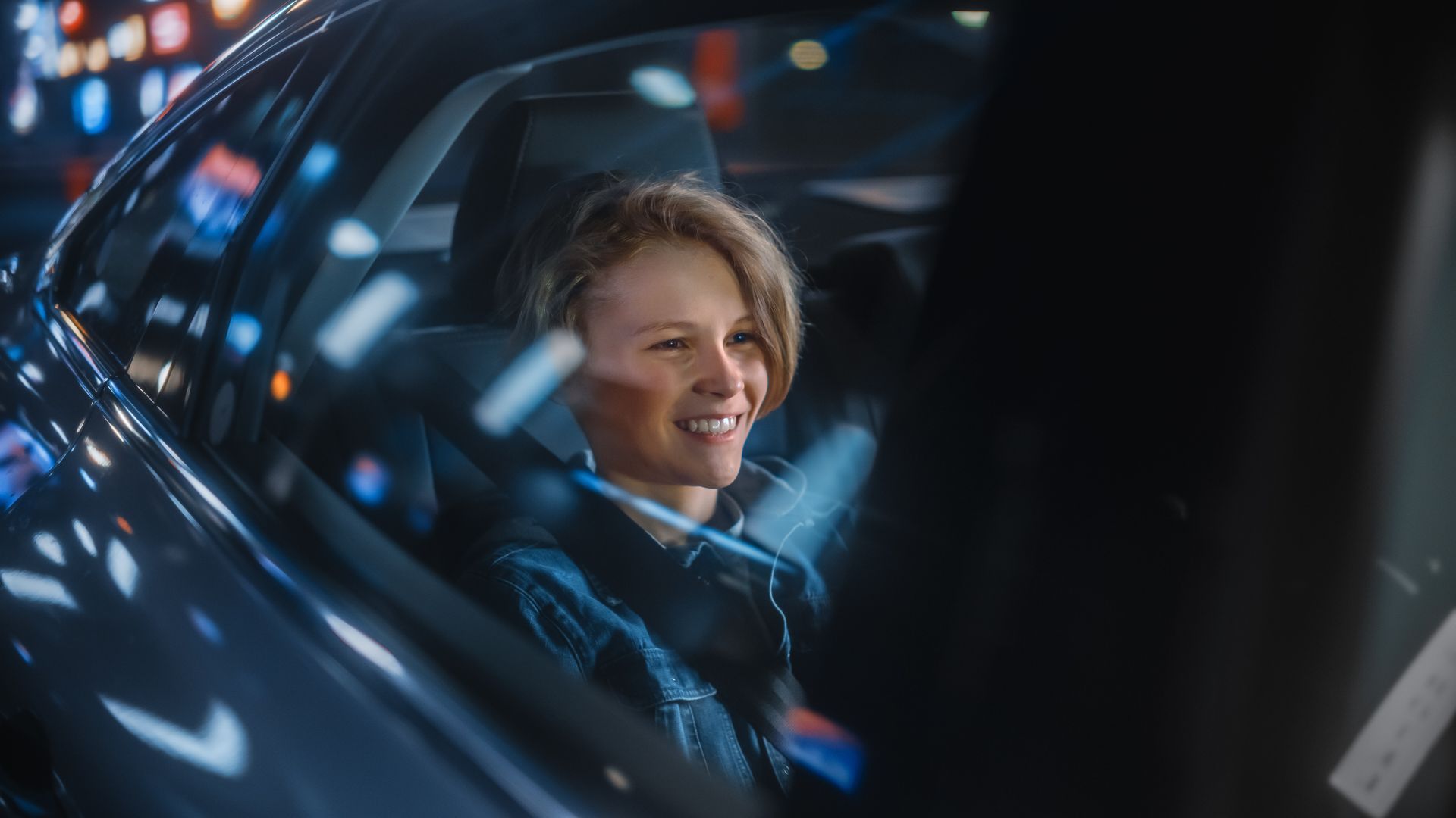 Jeune garçon souriant à l'arrière d'une voiture qui circule dans la nuit 