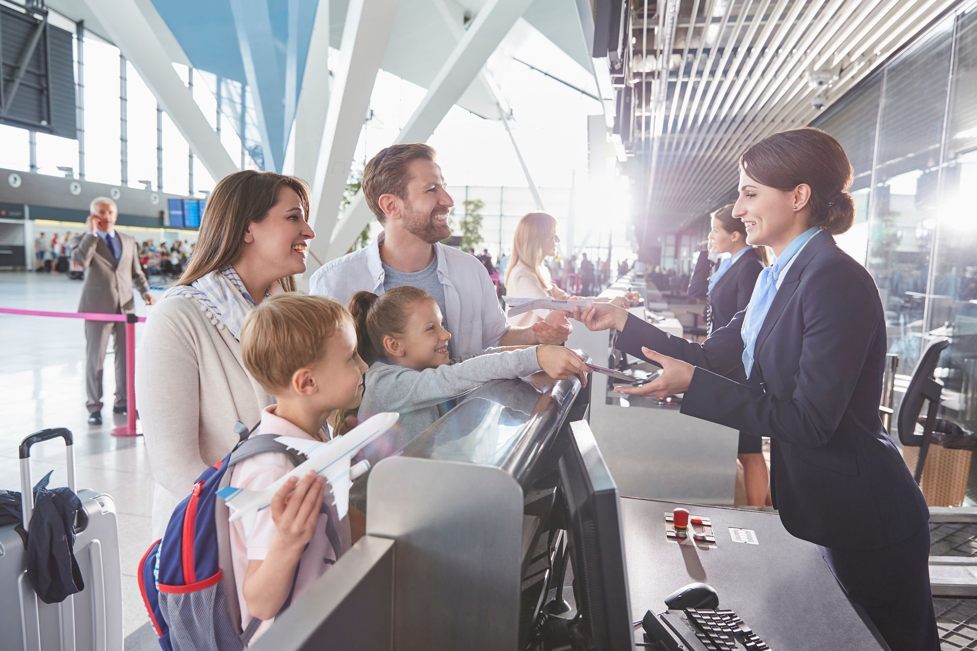 Famille avec enfants enregistrant leurs bagages au comptoir d'un aéroport