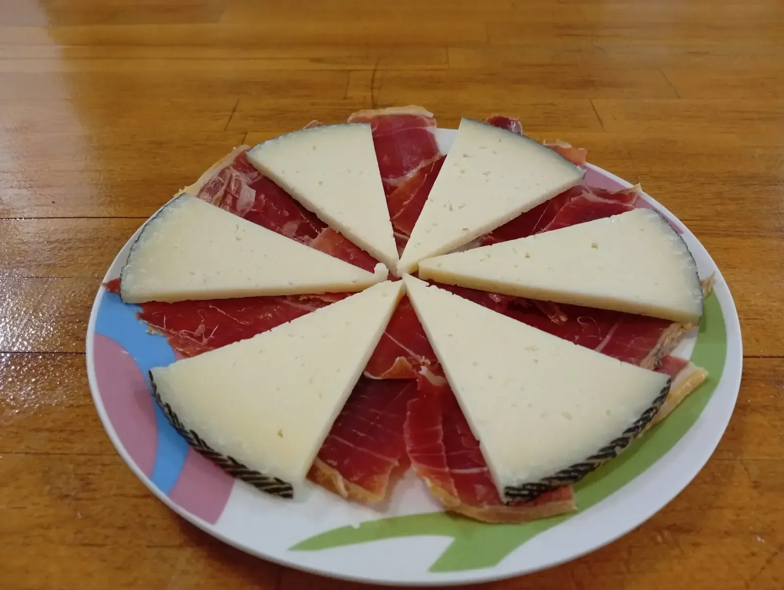 Plato con lonchas de queso dispuestas alrededor de lonchas de carne roja.
