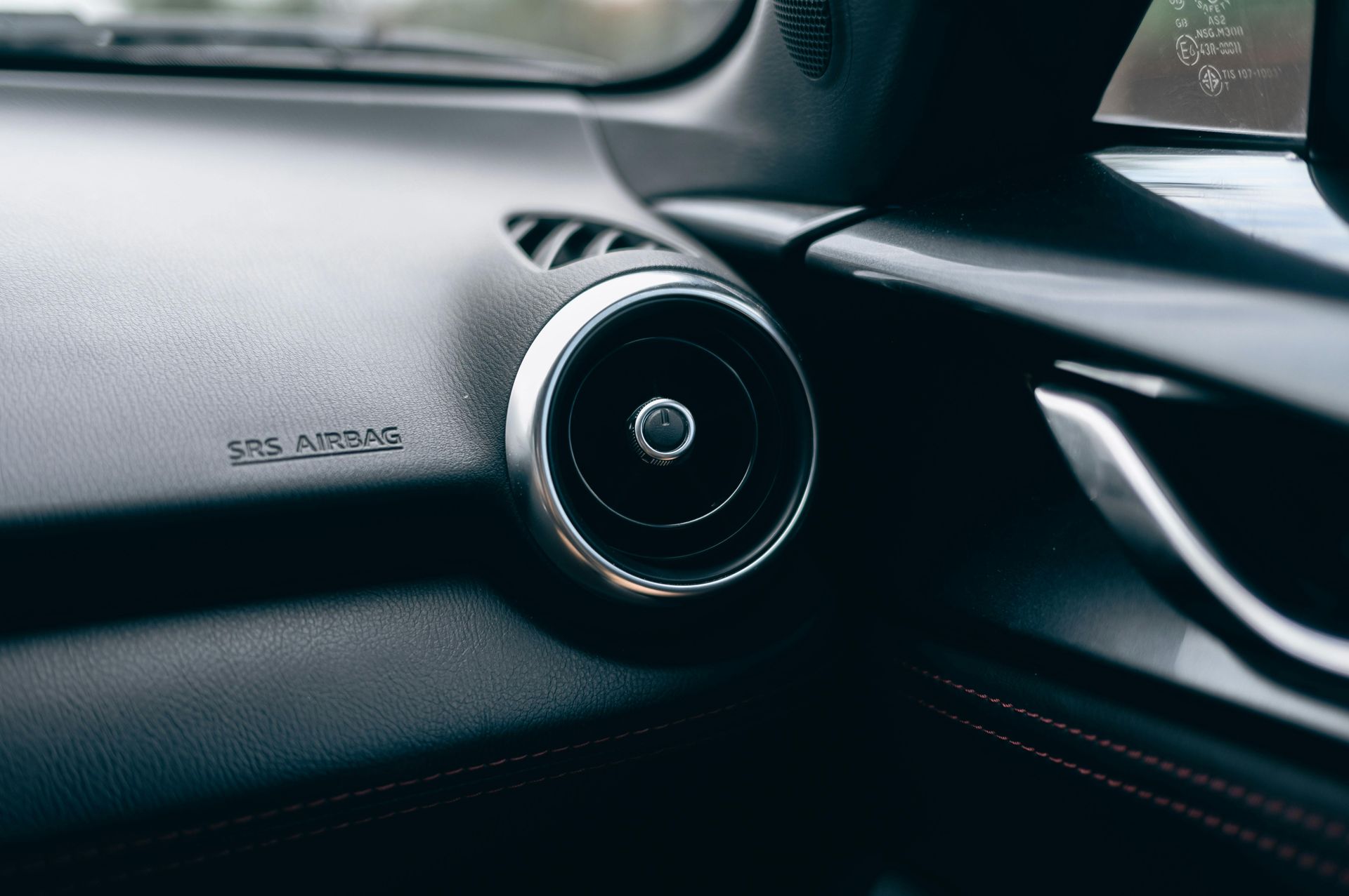 Detalhe do painel interno do carro com saída de ar e texto 