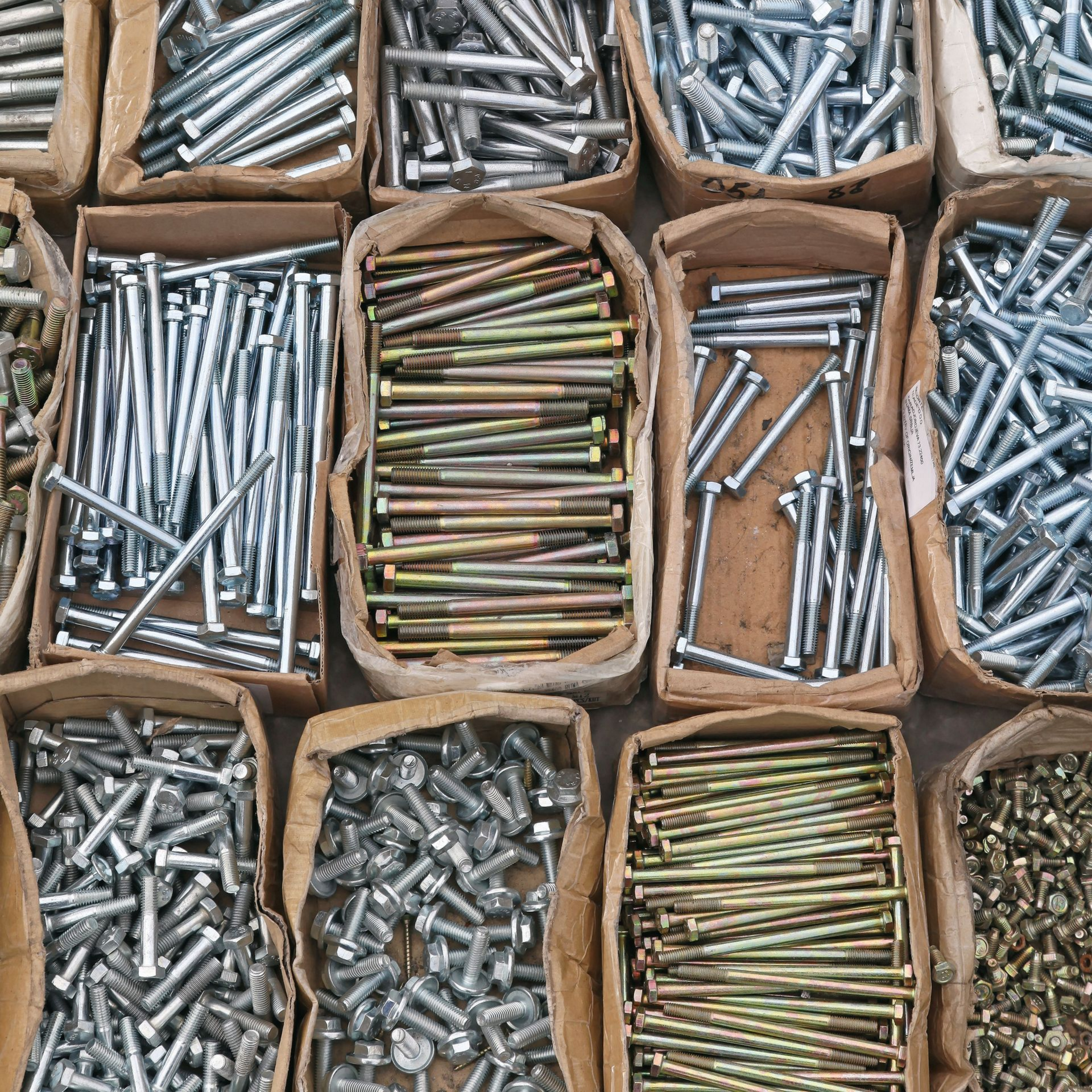 Assortiment de boulons et de vis, rangés dans des boîtes en carton pour le rangement de la quincaillerie.