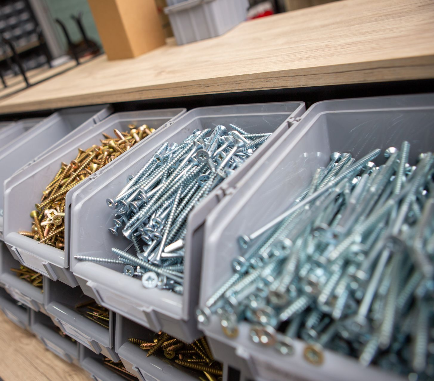 Des rangées de bacs gris contenant diverses vis.