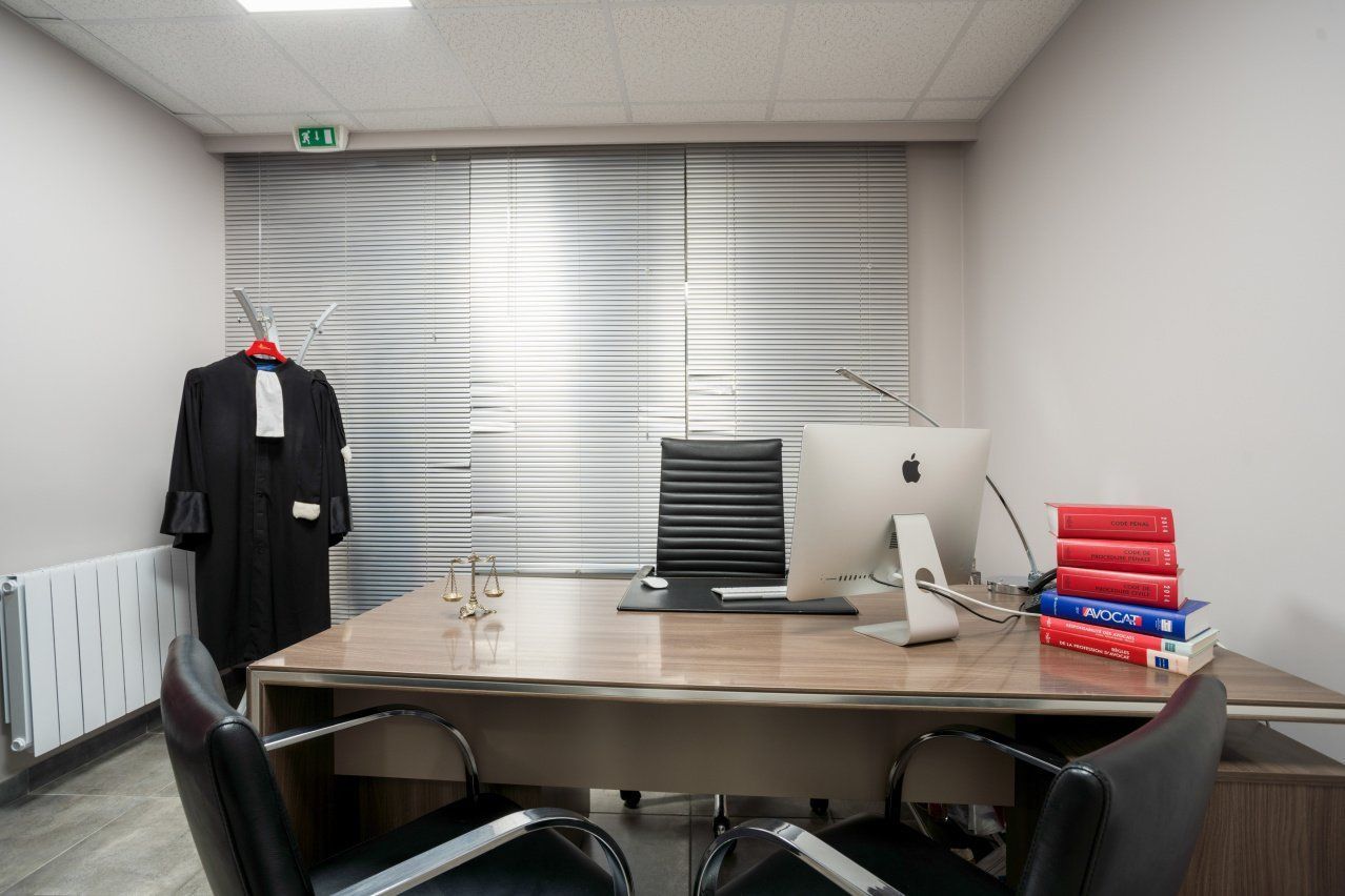 Bureau de Maître Zouaoui avec une robe d'avocat, une balance, un ordinateur et des livres