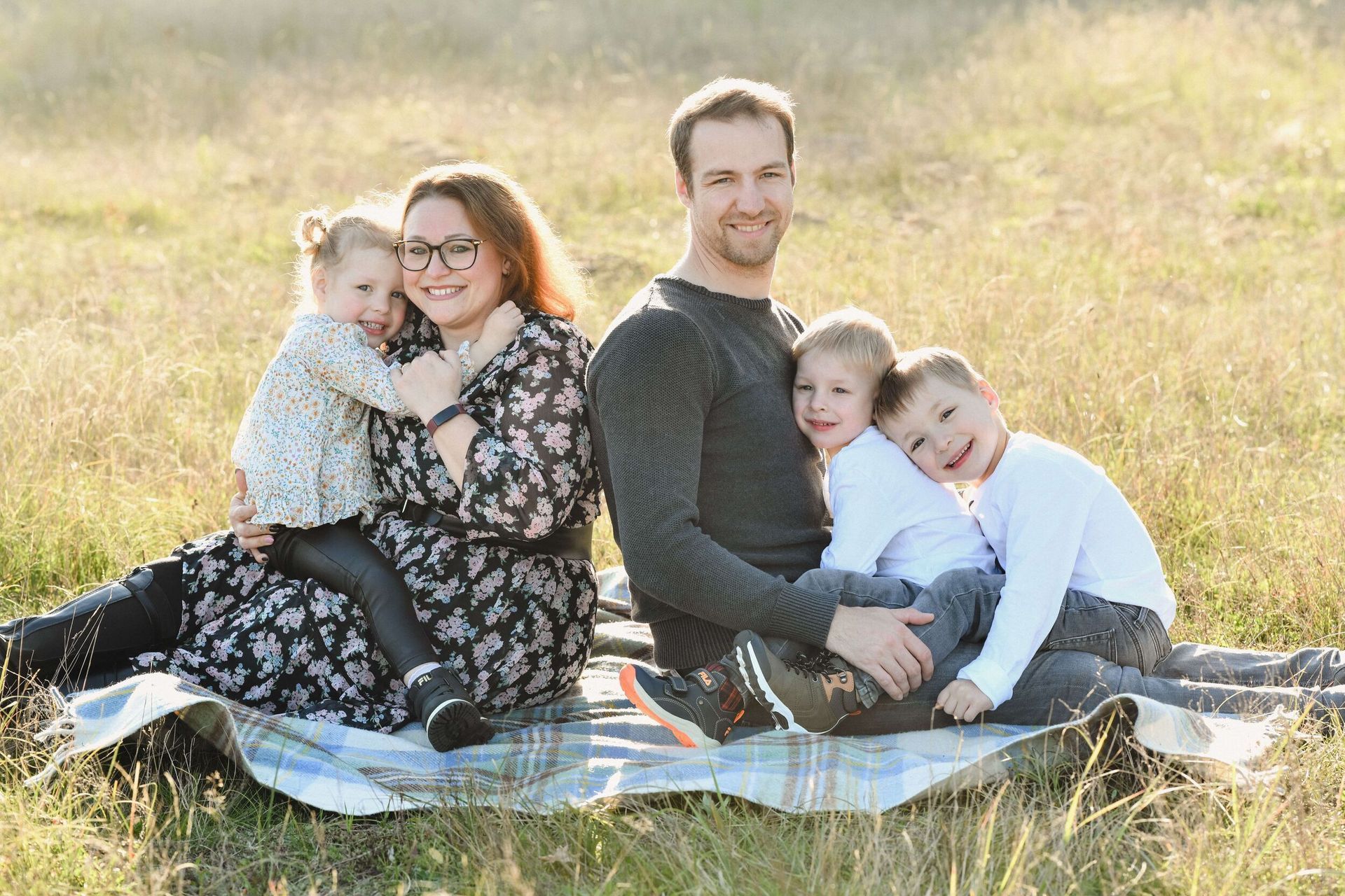 Eine Familie sitzt auf einer Decke auf einem Feld.