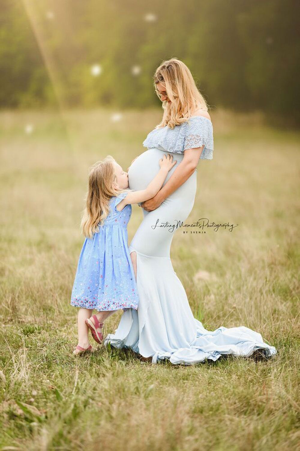 Eine schwangere Frau und ein kleines Mädchen stehen auf einem Feld.