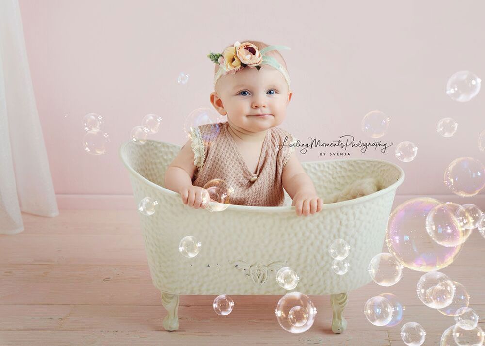Ein Baby sitzt in einer Badewanne, umgeben von Seifenblasen.
