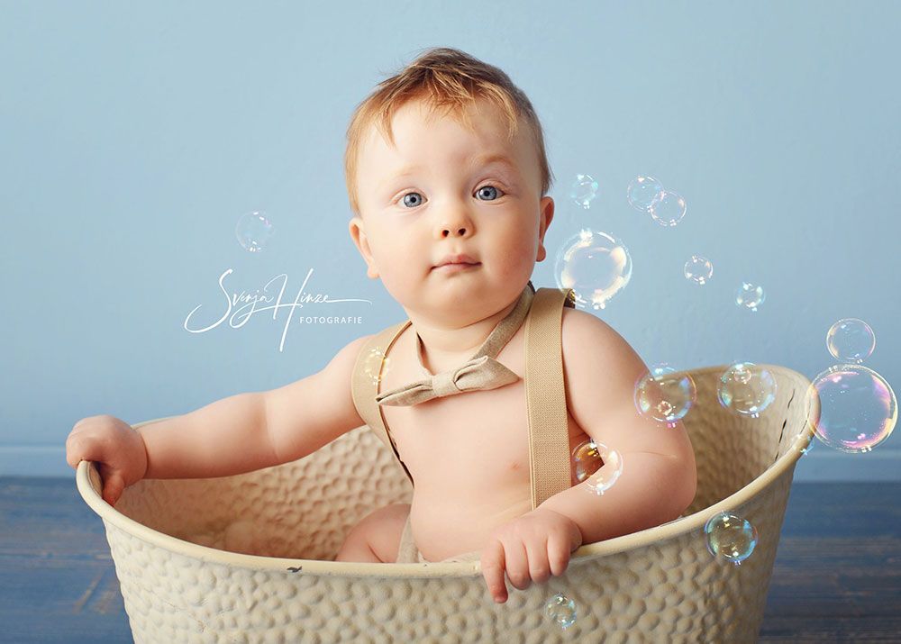 Ein Baby sitzt in einem Korb, umgeben von Seifenblasen.