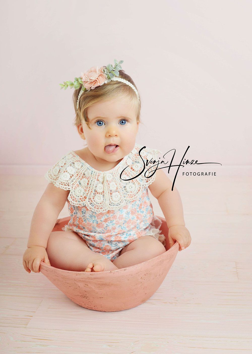 Ein kleines Mädchen sitzt in einer rosa Schüssel.