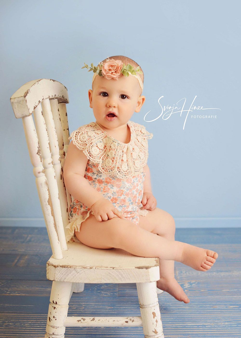 Ein kleines Mädchen sitzt auf einem weißen Stuhl.