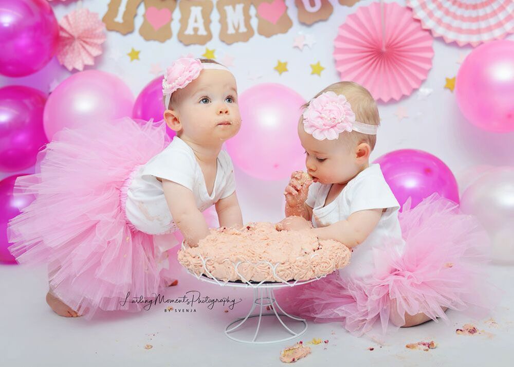 Zwei kleine Mädchen in rosa Tutus essen einen Kuchen.