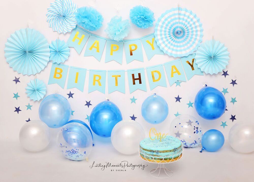 Eine Geburtstagstorte ist von blauen und weißen Luftballons und Dekorationen umgeben.