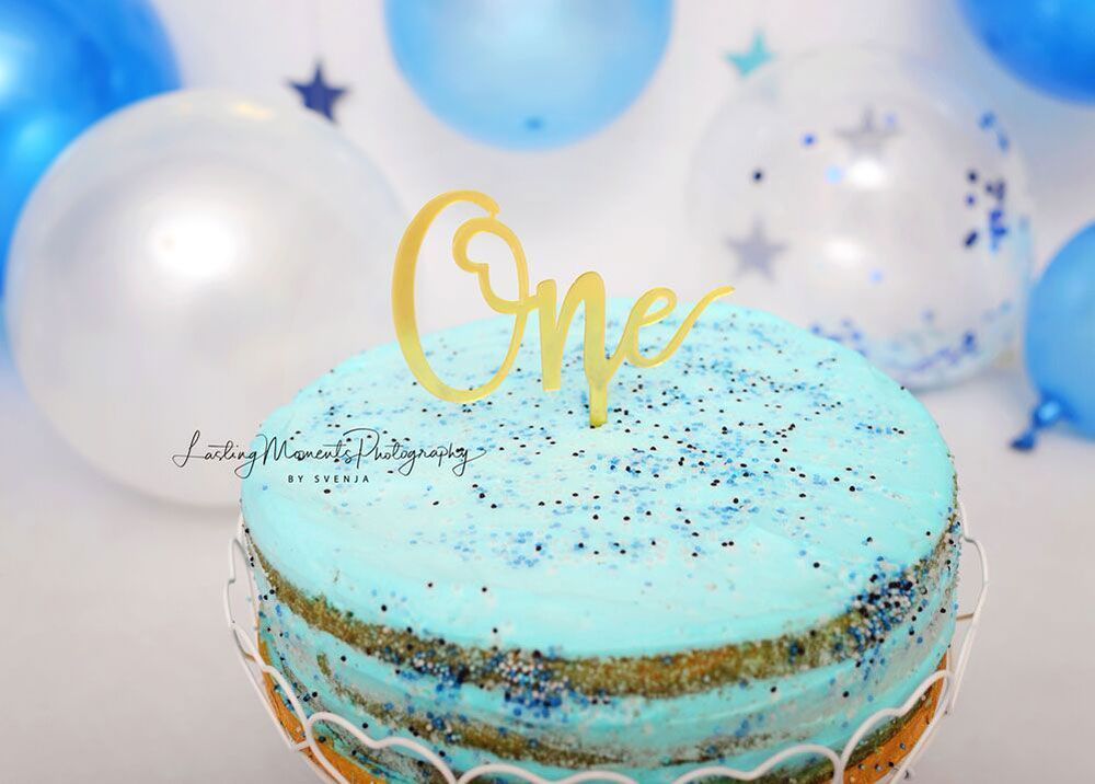 Ein blau-goldener Kuchen mit einem Kuchenaufsatz obendrauf.