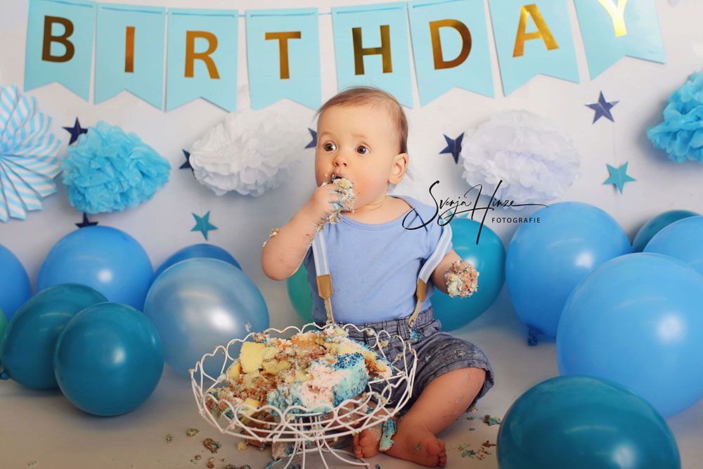 Ein Baby sitzt auf dem Boden und isst einen Geburtstagskuchen.