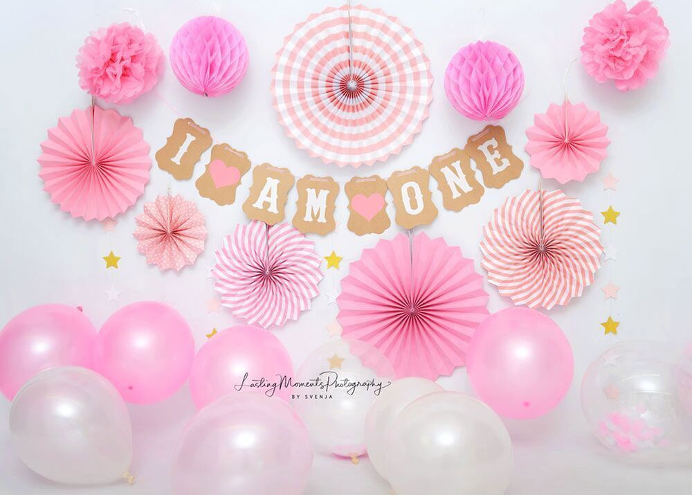 Der erste Geburtstag eines Mädchens wird mit rosa Luftballons und Papierfächern gefeiert.