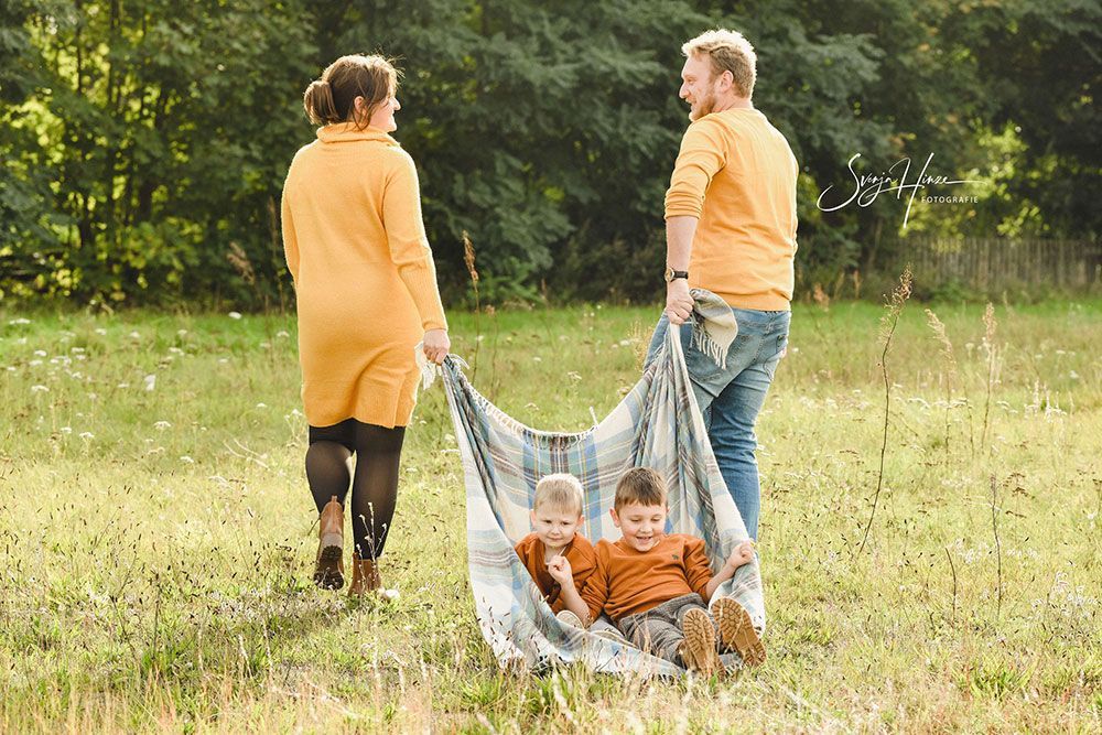 Eine Familie steht mit einer Decke in der Hand auf einem Feld.
