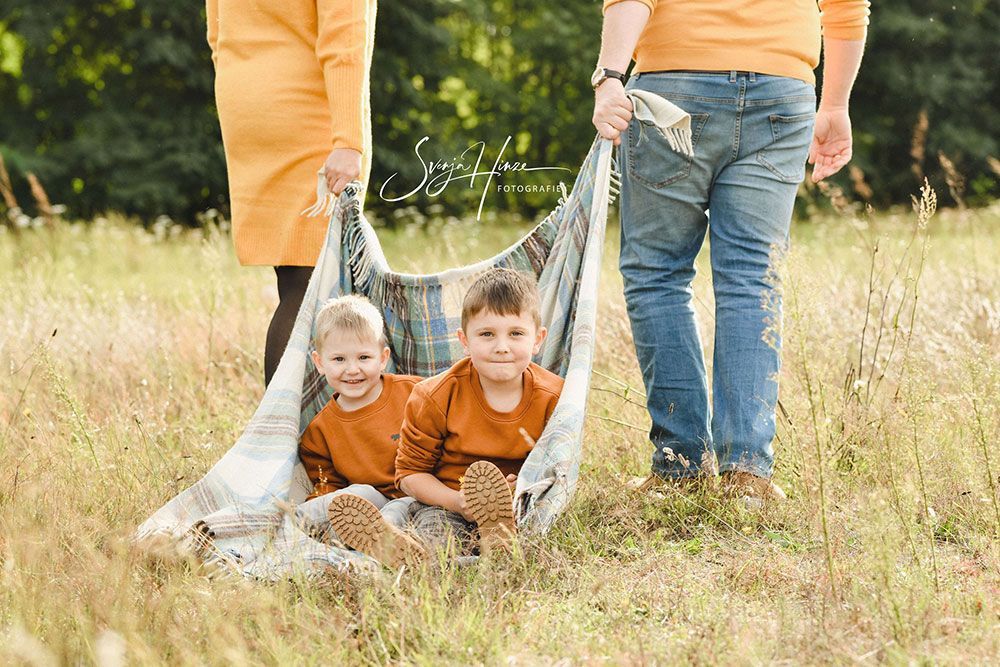 Eine Familie steht mit einer Decke in der Hand auf einem Feld.