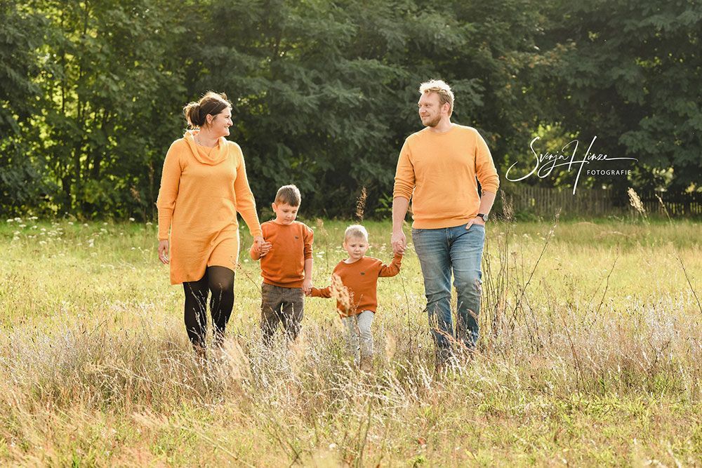 Eine Familie geht Hand in Hand durch ein Feld.