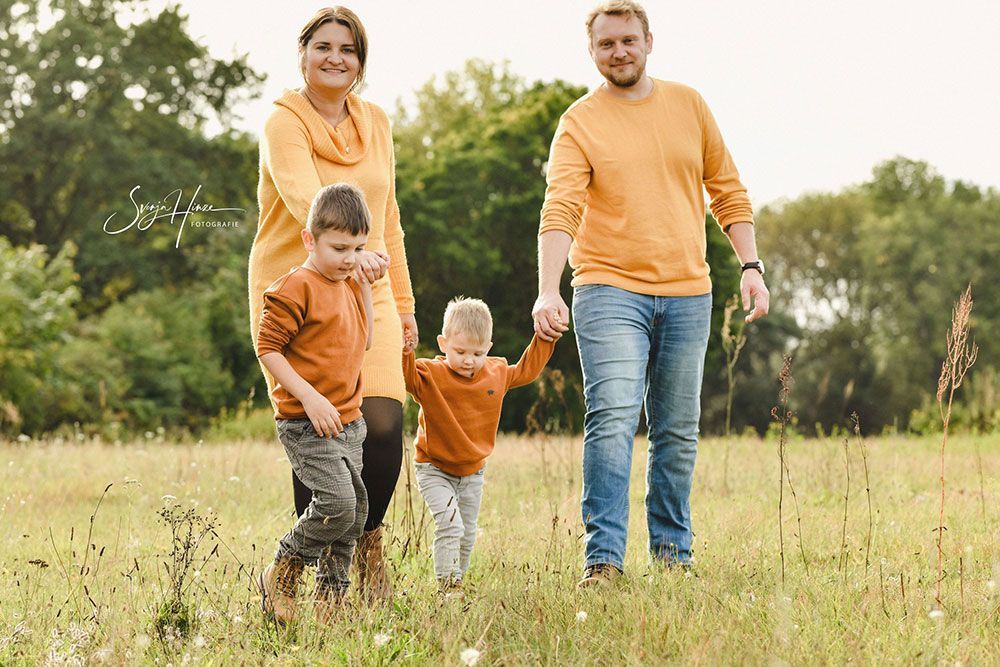 Eine Familie geht Hand in Hand durch ein Feld.