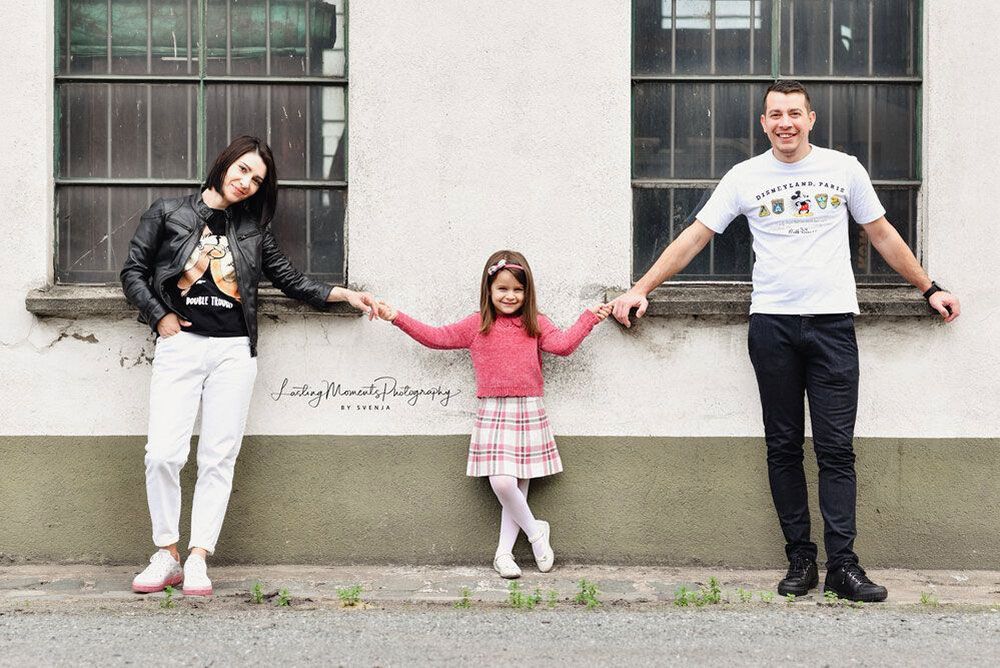 Eine Familie steht vor einem Gebäude und hält Hände.