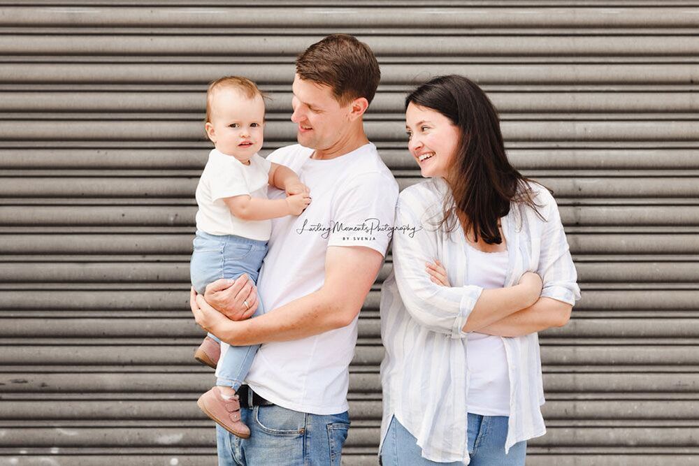 Ein Mann und eine Frau stehen nebeneinander und halten ein Baby.