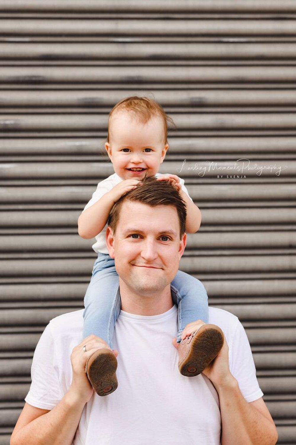 Ein Mann trägt ein Baby auf seinen Schultern.