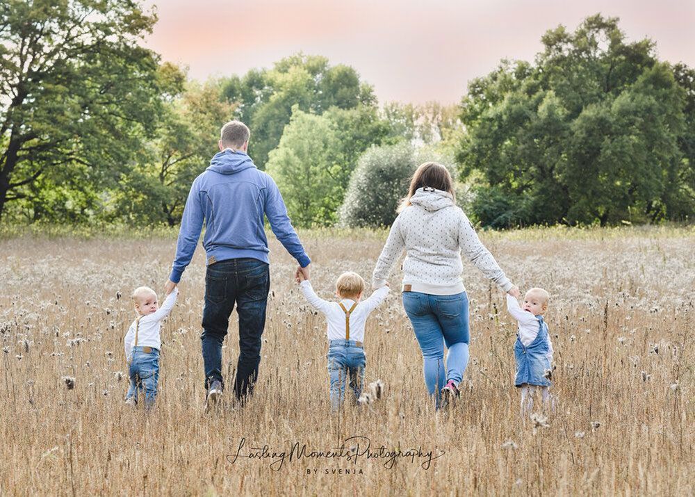 Eine Familie geht Hand in Hand durch ein Feld.