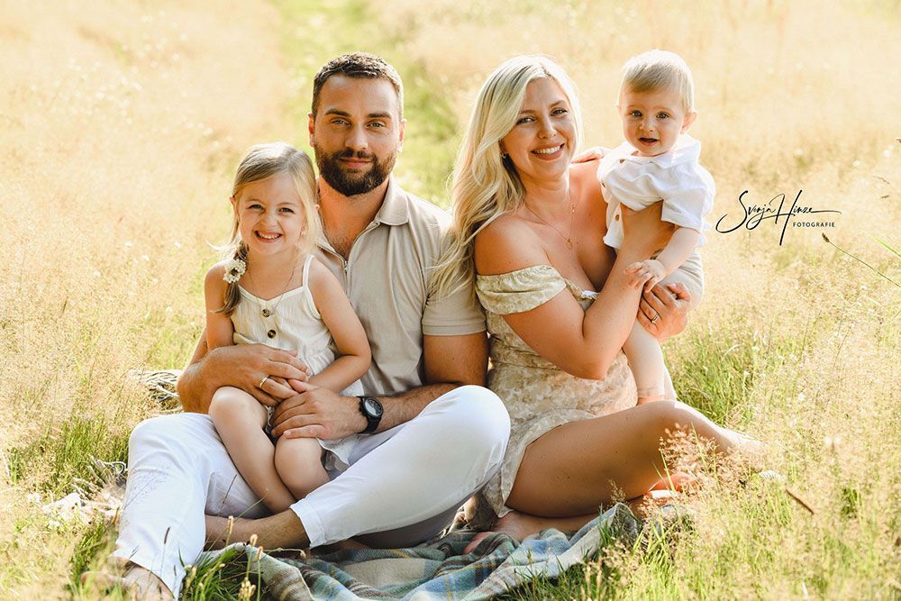 Eine Familie sitzt auf einer Decke im Gras.