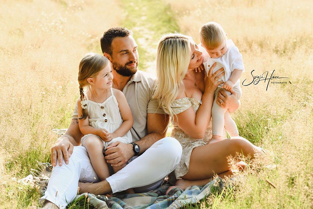 Eine Familie sitzt auf einer Decke auf einem Feld.