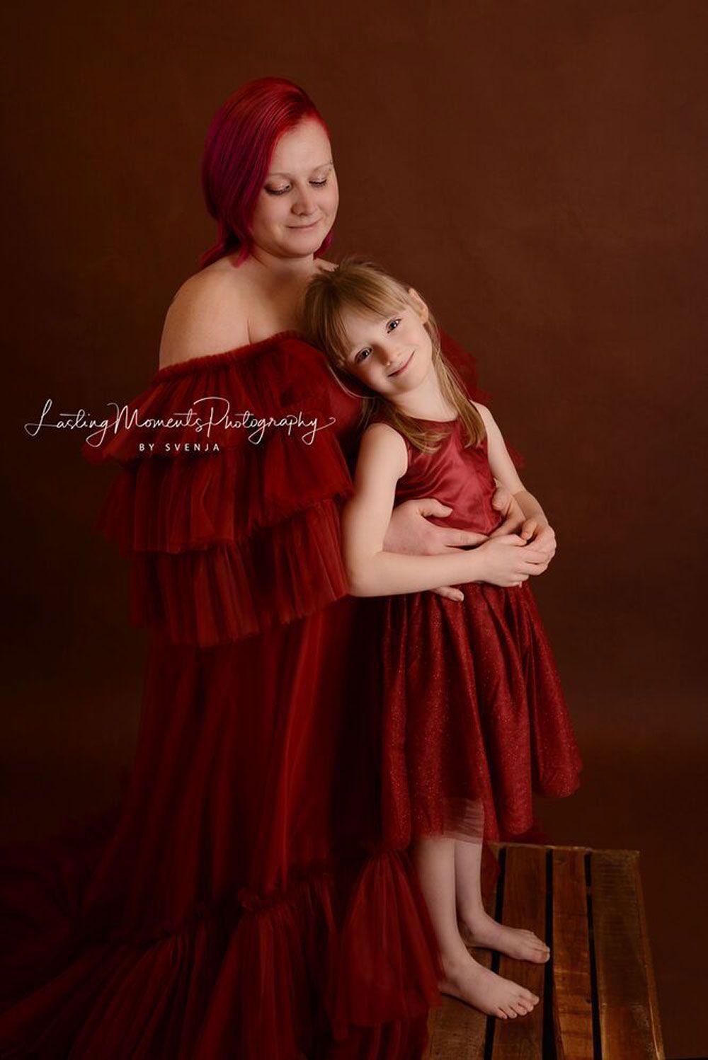 Eine Frau und ein kleines Mädchen in roten Kleidern stehen nebeneinander.