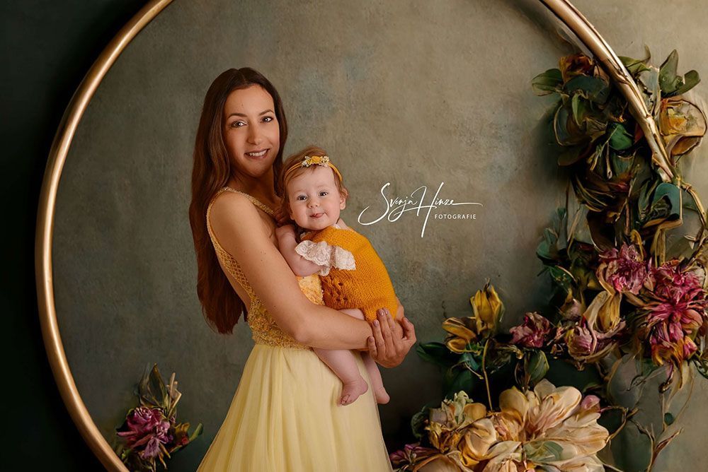 Eine Frau in einem gelben Kleid hält ein Baby in ihren Armen.