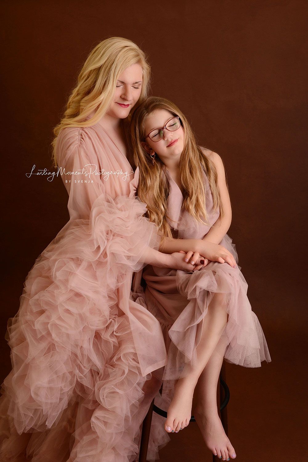 Eine Mutter und ihre Tochter sitzen in passenden Kleidern nebeneinander.