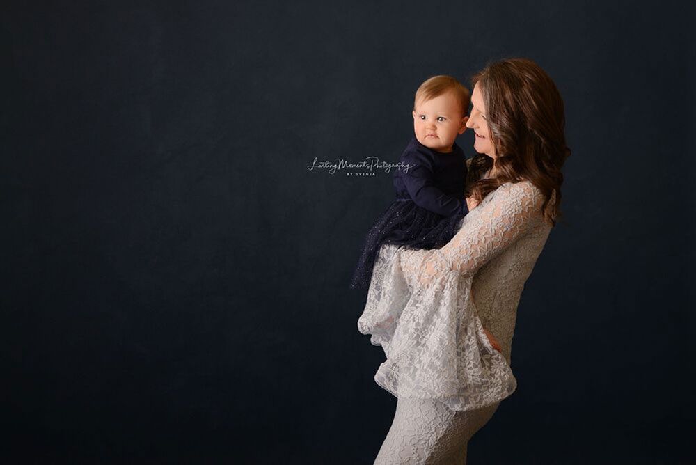 Eine Frau in einem weißen Kleid hält ein Baby in ihren Armen.