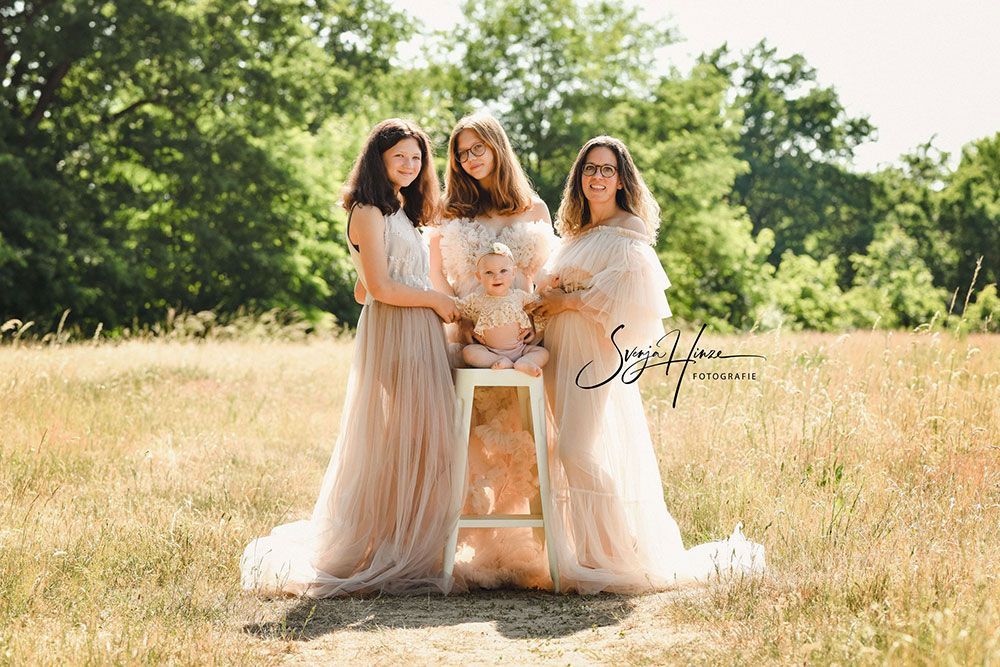 Eine Gruppe von Frauen posiert auf einem Feld für ein Foto mit einem Baby.