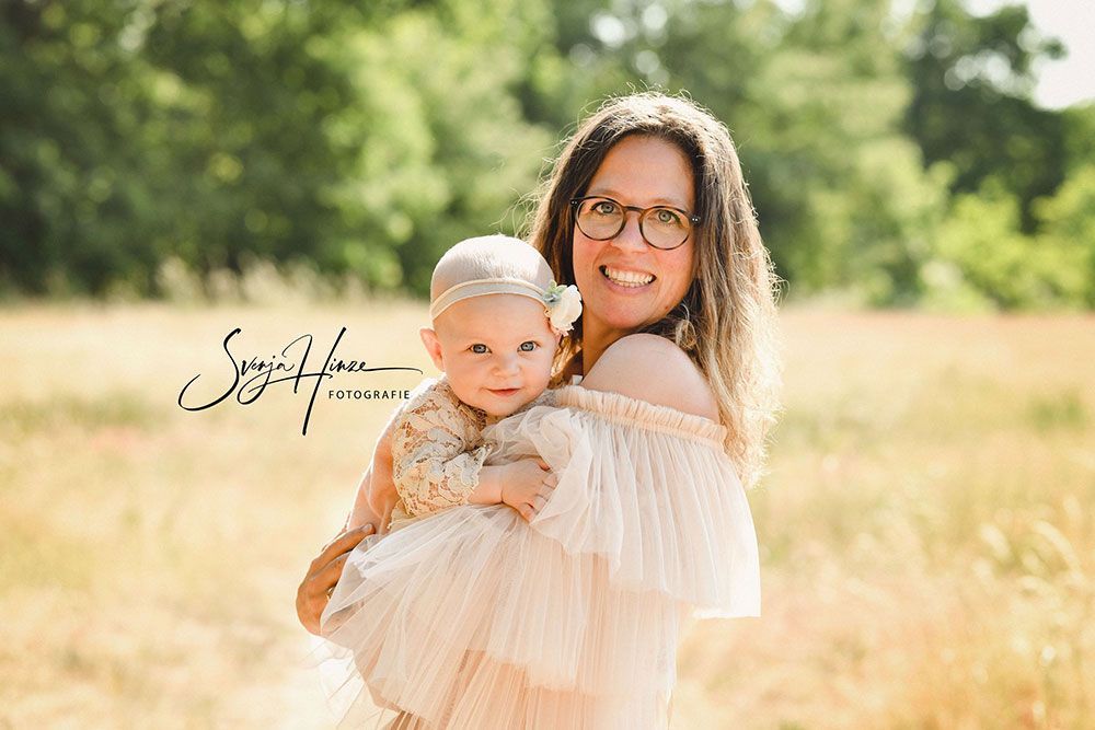 Eine Frau hält auf einem Feld ein Baby im Arm.