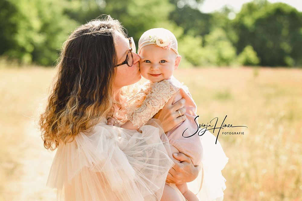 Eine Frau küsst auf einem Feld ein Baby auf die Wange.