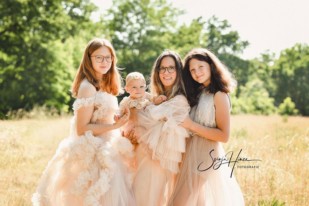 Eine Gruppe von Frauen steht nebeneinander auf einem Feld und hält ein Baby.