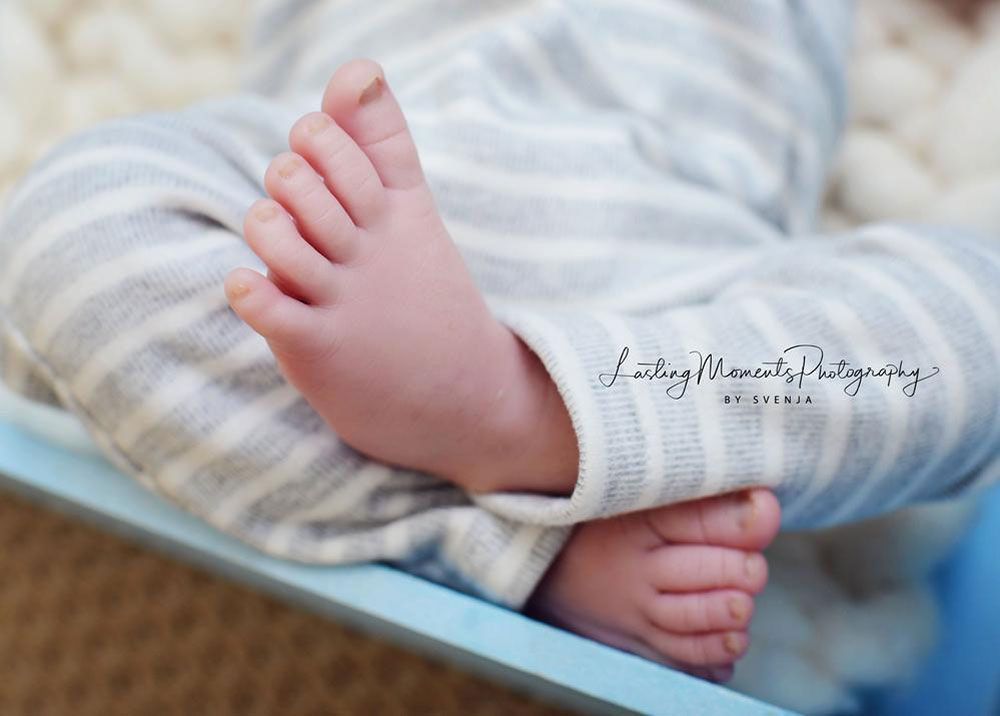 Eine Nahaufnahme der Füße eines Babys in einem blauen Kinderbett