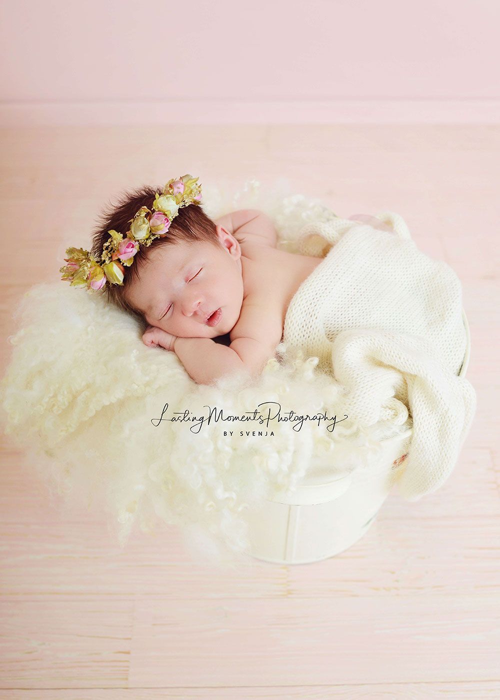 Ein neugeborenes Baby mit einem Blumenkranz schläft in einem Korb.