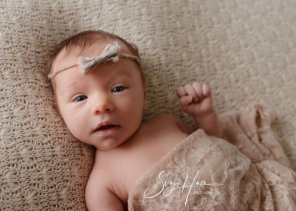 Ein Neugeborenes ist in eine Decke gewickelt und trägt ein Stirnband.