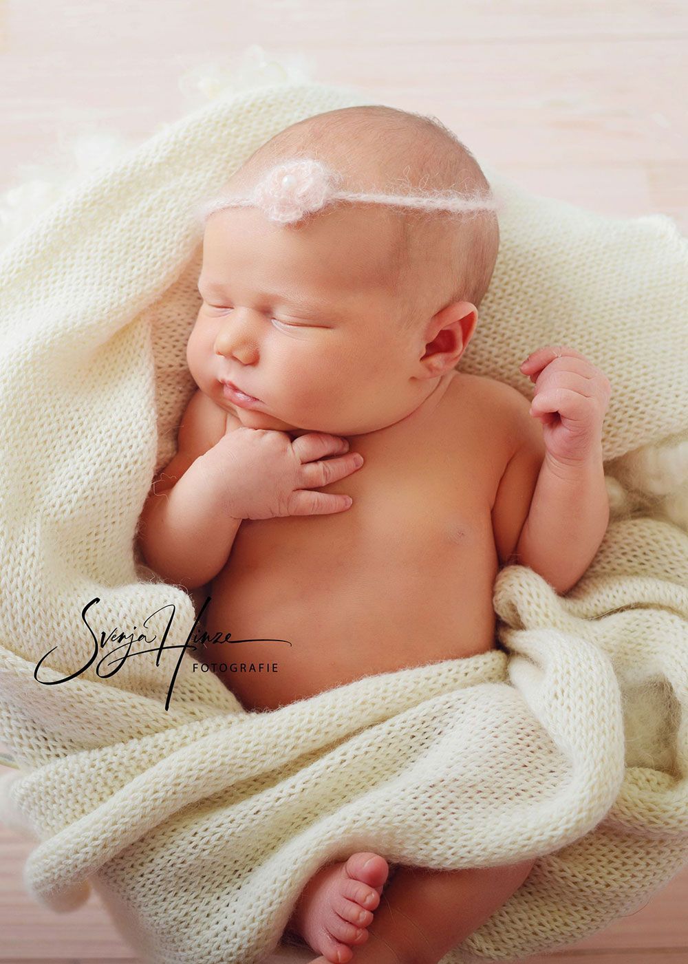 Ein Neugeborenes, in eine weiße Decke gehüllt, schläft.