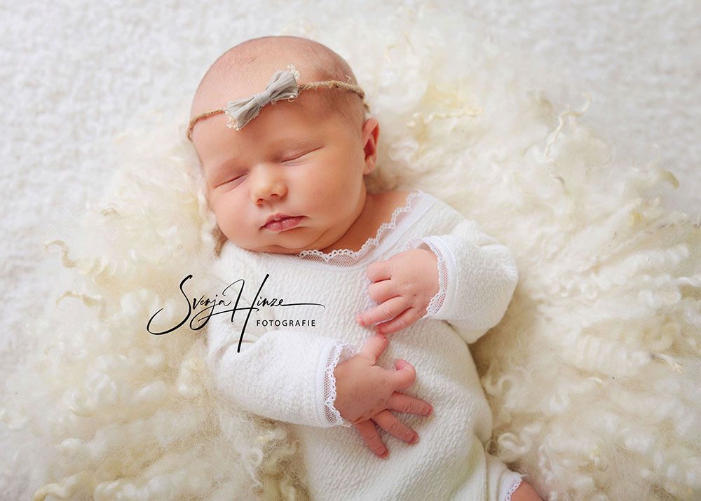 Ein Neugeborenes schläft auf einer weißen Decke.