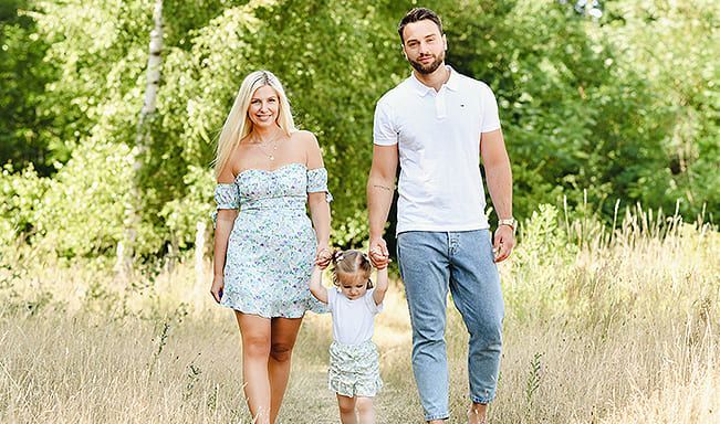 Eine Familie geht Hand in Hand durch ein Feld.