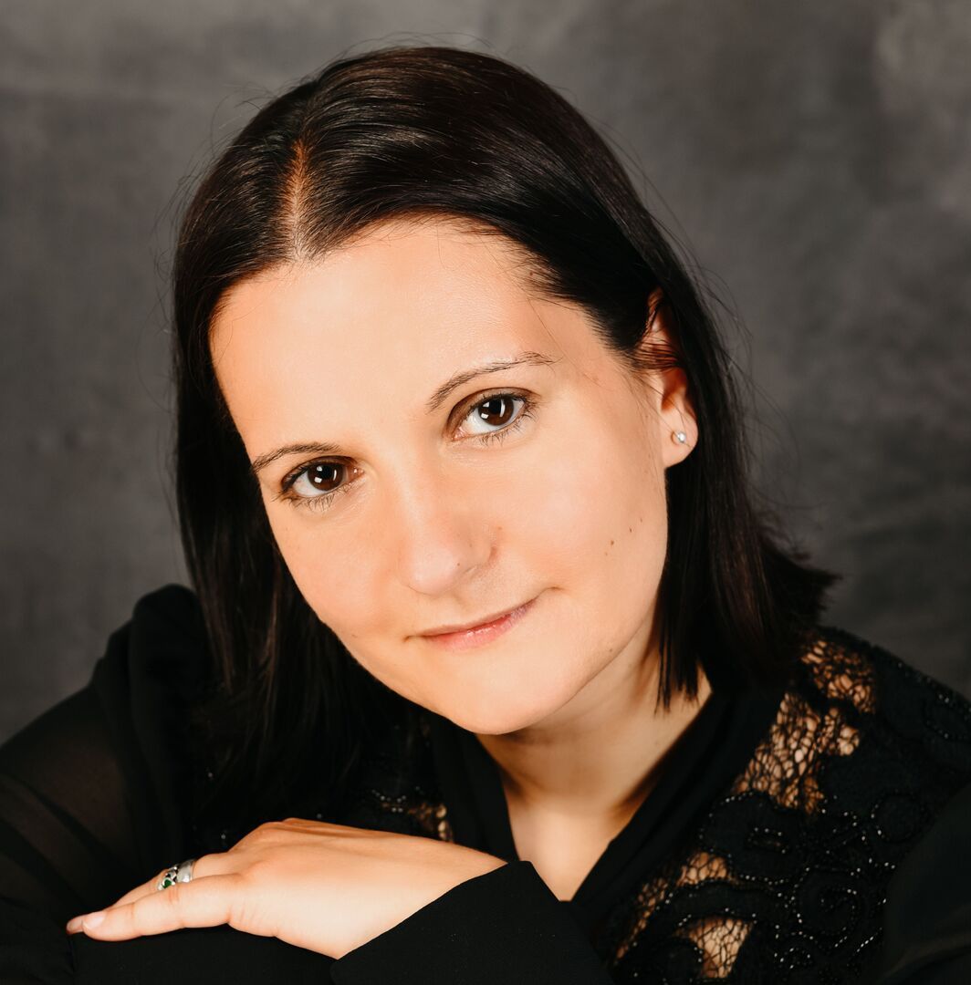 Eine Frau mit einem Ring am Finger blickt in die Kamera