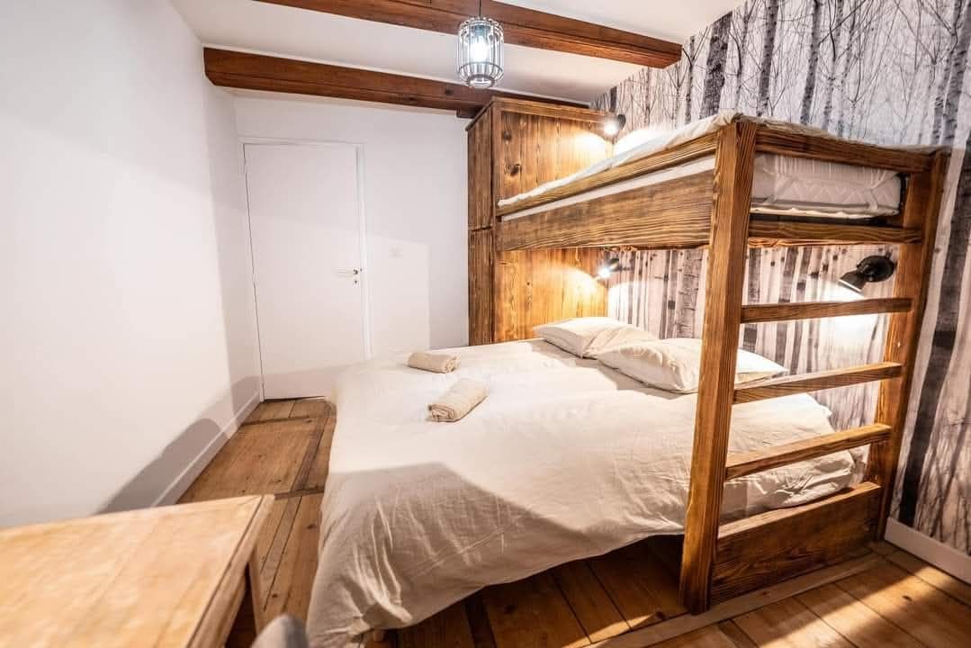 Chambre avec un lit superposé en bois au-dessus d'un lit double, style rustique avec literie blanche.