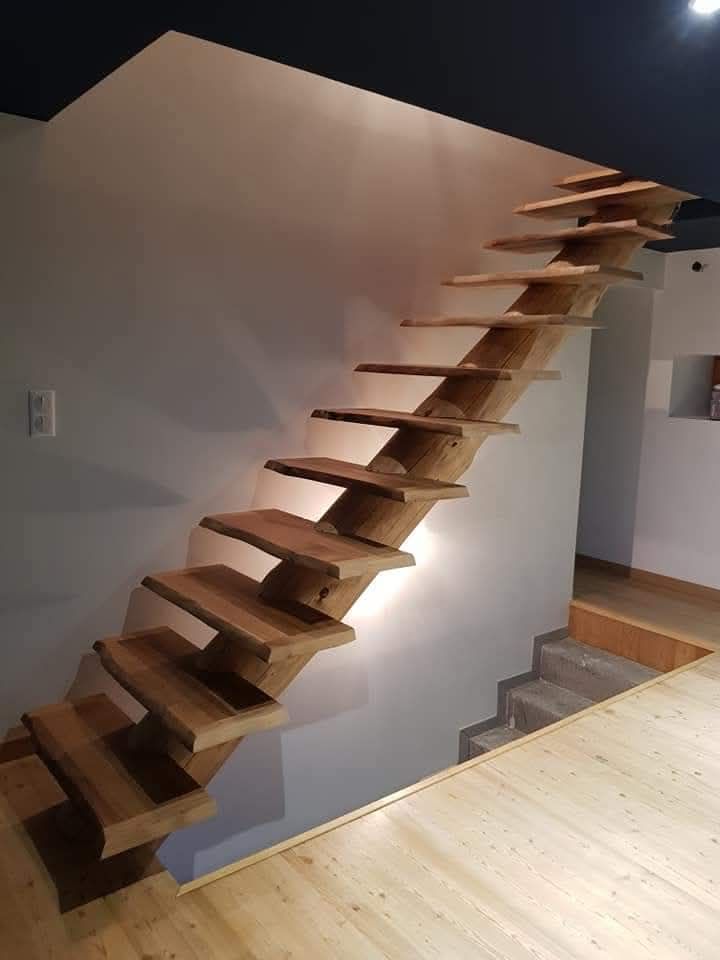 Escalier flottant en bois contre un mur blanc ; éclairé par en dessous. Vue intérieure.