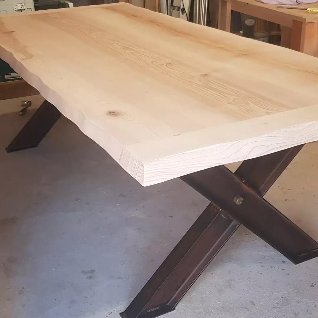 Table en bois avec plateau en bois naturel et base en acier à pieds croisés.