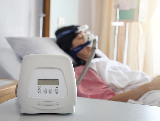 Una mujer está acostada en una cama de hospital con una máscara de oxígeno en la cara.