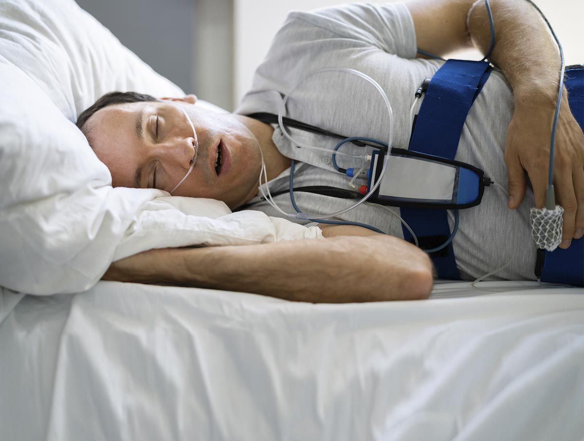 Un hombre está acostado en una cama de hospital con una máscara de oxígeno en el pecho.